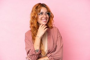 Woman with red hair against a light pink background